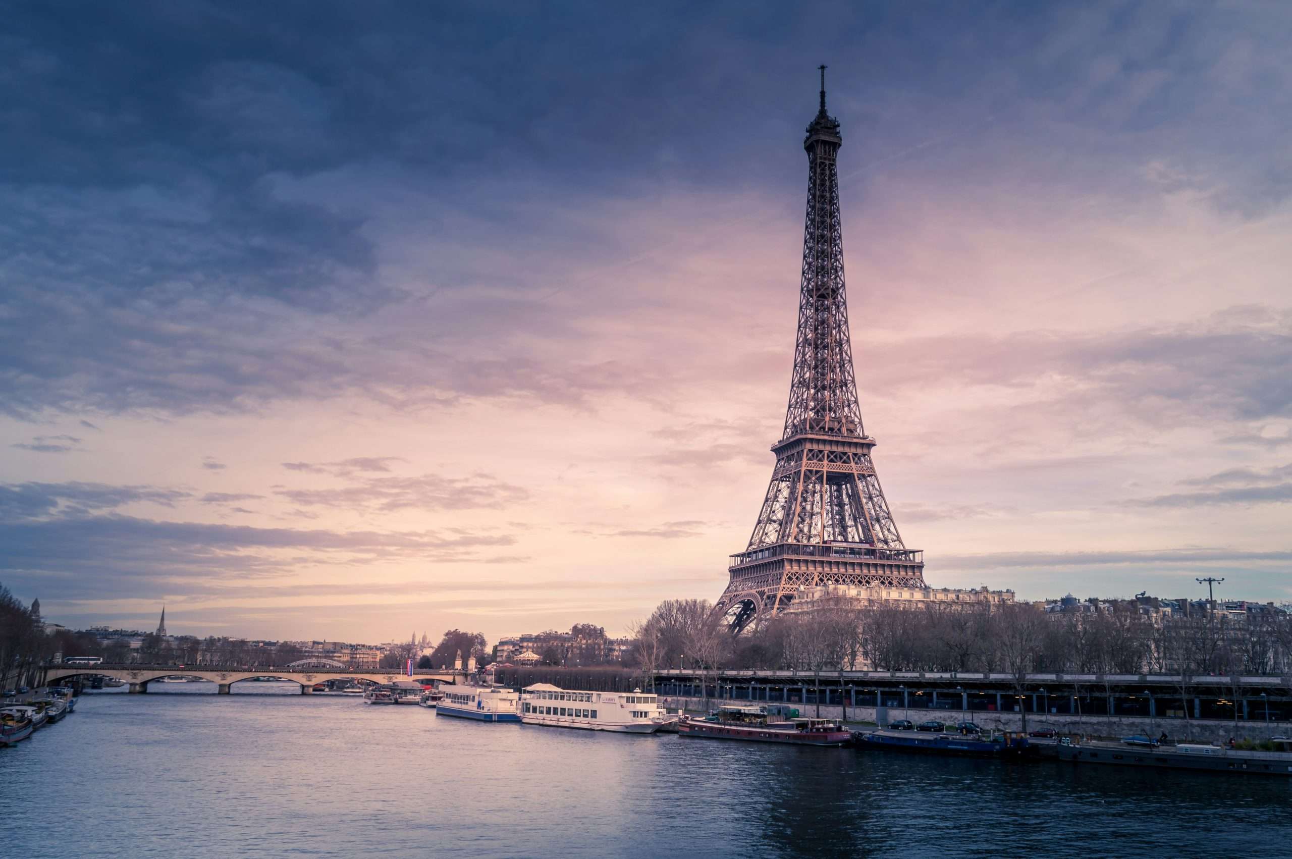 Eiffel Tower against sunset with river in foreground | Photo by Chris Karidis on Unsplash