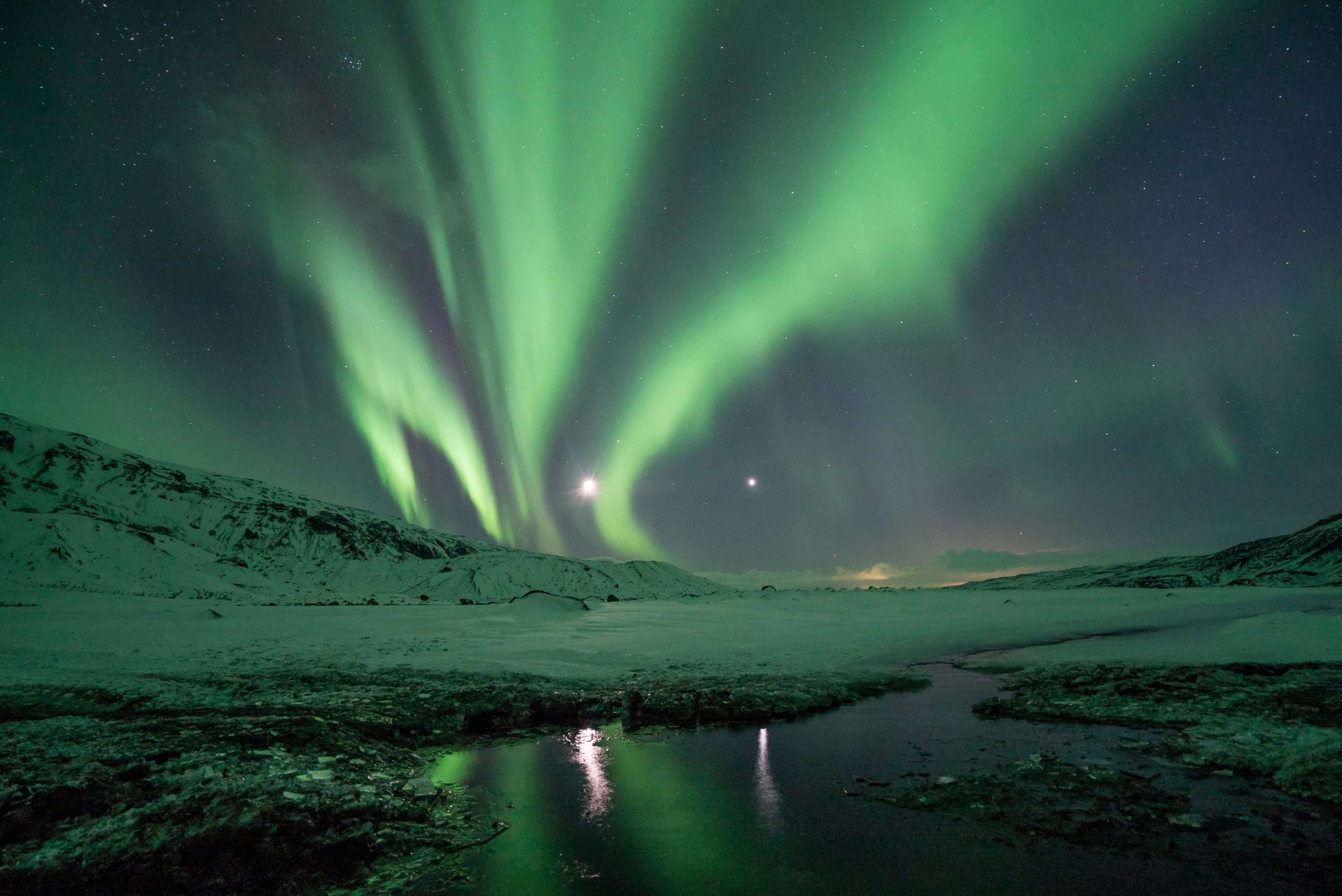 Northern Lights in the sky above a snowy landscape | Photo by Jonatan Pie on Unsplash