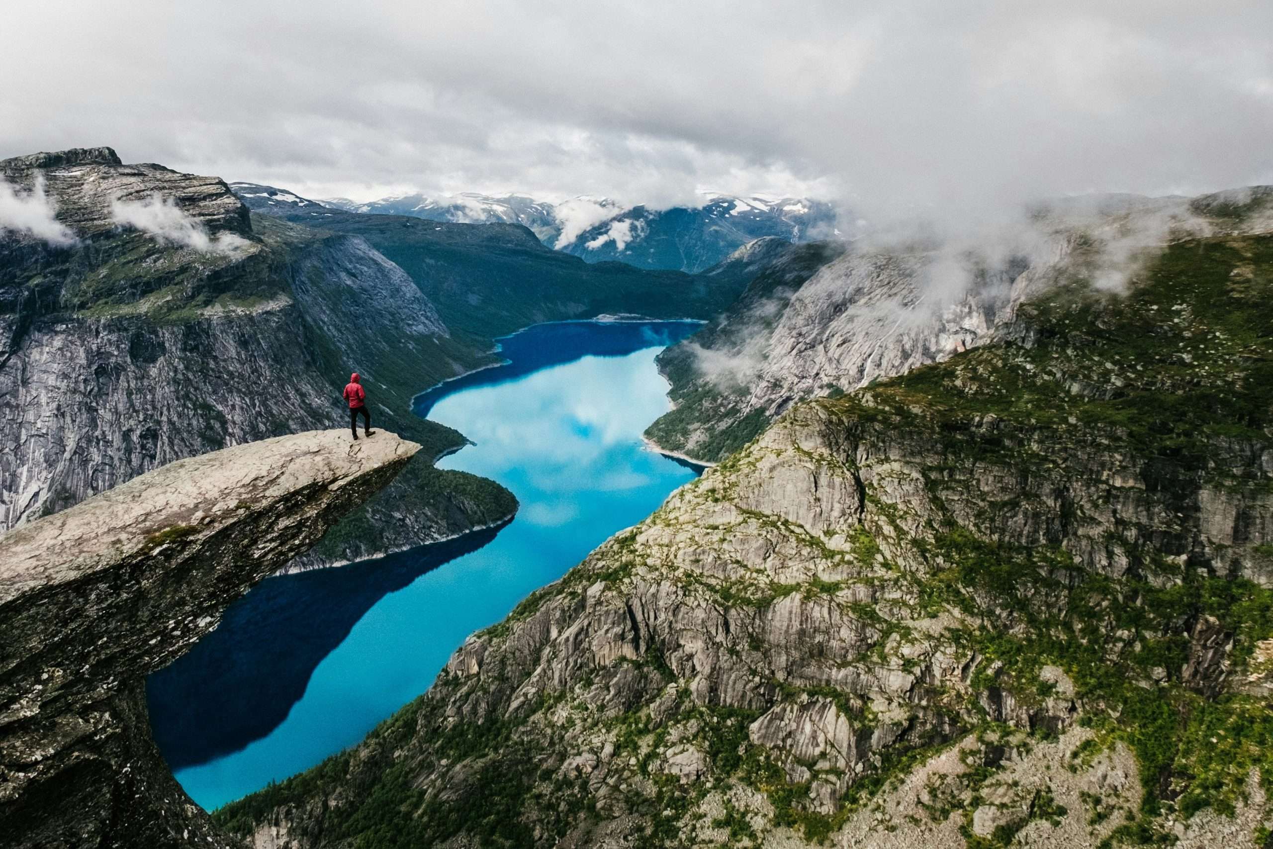 Man sitting on cliff overlooking deep fjord gorge | Photo by Robert Bye on Unsplash