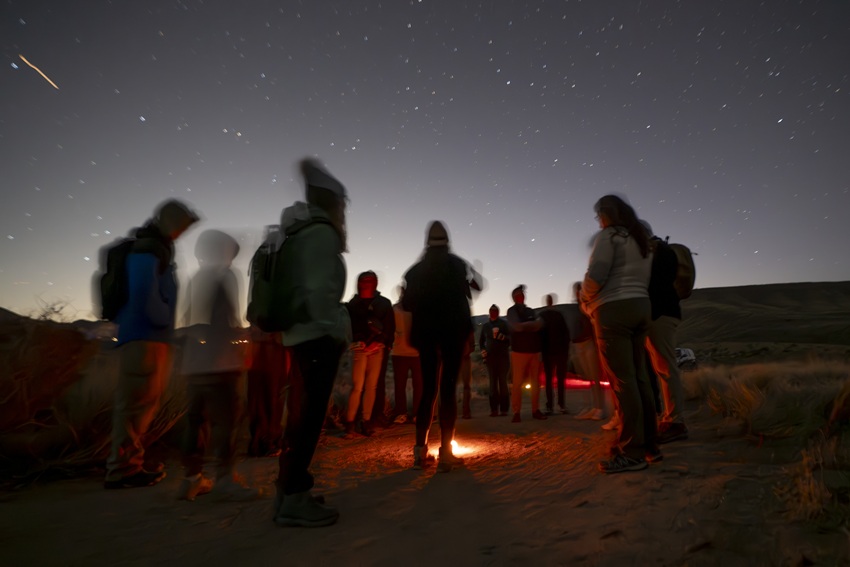 Group of travelers gathered under a starlit sky during a guided stargazing tour in Joshua Tree National Park.