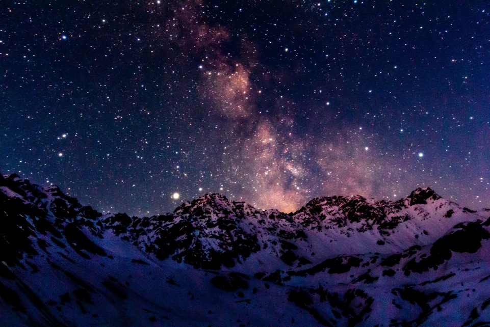 Snow-covered Swiss Alps under a dazzling night sky filled with stars and the Milky Way, creating a breathtaking view of Switzerland’s mountain landscape.