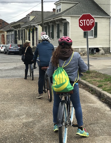 Three people with helmets riding bicycles along the street in New Orleans