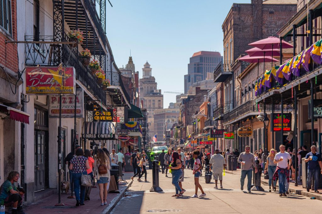 Vibrant street scene in New Orleans with colorful store signs and lots of people exploring by foot