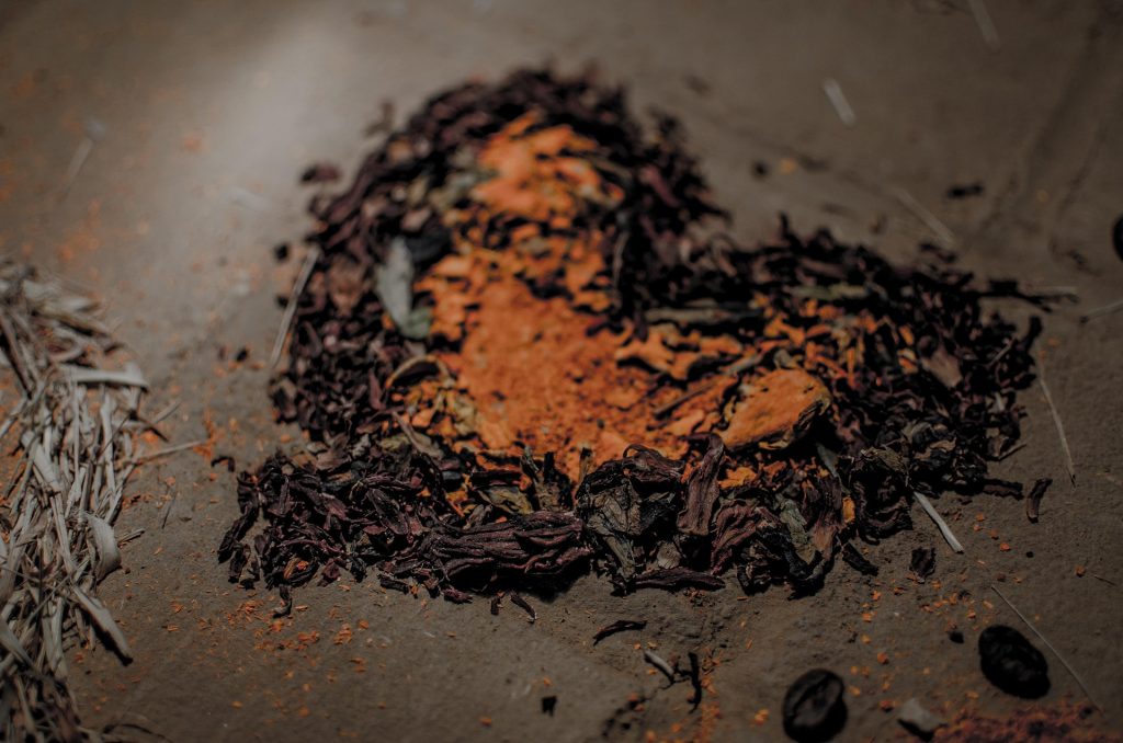 Heart-shaped display of dried leaves, dried flowers, and orange-colored ground minerals for voodoo ritual