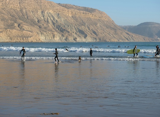 Beginner surfers practicing in the waves during a surf lesson on Essaouira Beach, Morocco.